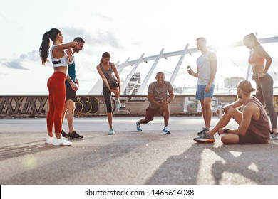 Full length of people in sports clothing warming up and stretching while exercising outdoors                