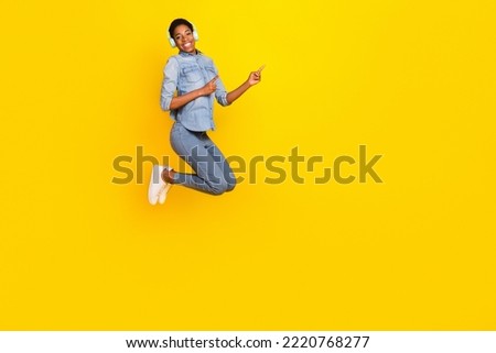 Full length photo of active person wireless earphones direct fingers empty space isolated on yellow color background