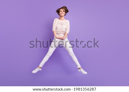 Full length photo of adorable charming young lady dressed white shirt jumping high isolated purple color background