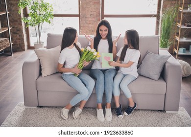 Full length photo of adorable daughters give flowers card excited positive lady hands palms up enjoy free time indoors