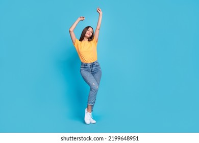 Full length photo of adorable dreamy girl dressed yellow t-shirt dancing closed eyes empty space isolated blue color background