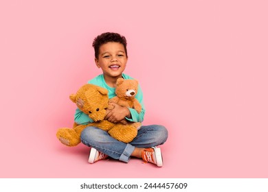 Full length photo of adorable little boy sit floor hold two teddy bears dressed stylish cyan garment isolated on pink color background - Powered by Shutterstock