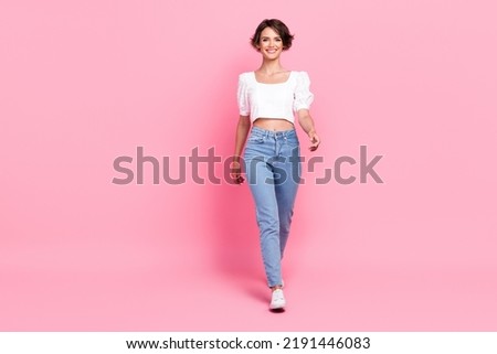 Full length photo of adorable pretty girl dressed white blouse walking empty space isolated pink color background