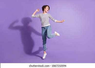 Full length photo of adorable young lady dressed casual clothes dancing looking empty space isolated purple color background