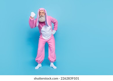 Full length photo of aggressive angry man pensioner dressed pink rabbit nightwear showing fist empty space isolated blue color background - Shutterstock ID 2262839101