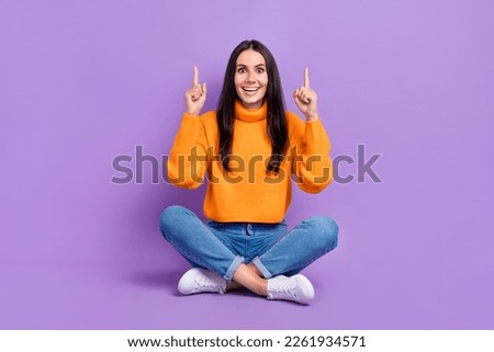 Full length photo of astonished positive lady sitting floor arm direct empty space special offer isolated on purple color background