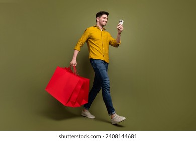 Full length photo of attractive brunet man wear stylish clothes carry packages step store mall center isolated on khaki color background - Powered by Shutterstock