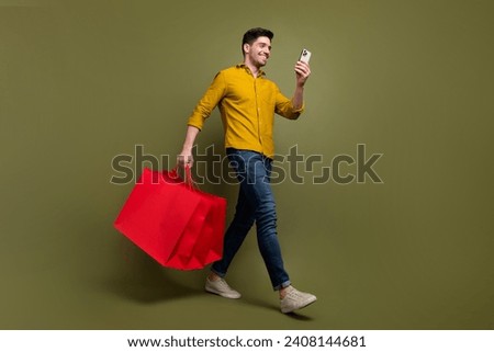 Full length photo of attractive brunet man wear stylish clothes carry packages step store mall center isolated on khaki color background