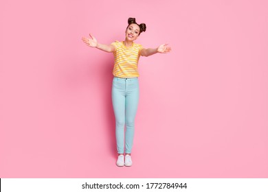 Full length photo of attractive charming lady two funny buns arms open waiting hugs beaming smile wear casual white yellow striped shirt trousers shoes isolated pastel pink color background
