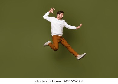 Full length photo of attractive cheerful guy wearing trendy clothes fighting empty space isolated on khaki color background
