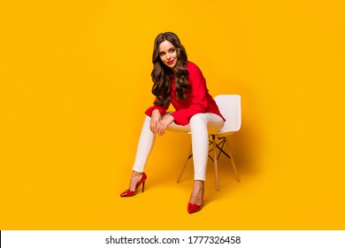 Full Length Photo Of Attractive Chic Business Lady Sit Bossy Comfy Chair Flirty Mood Look Side Empty Space Wear Red Shirt White Trousers High-heels Isolated Yellow Vivid Color Background