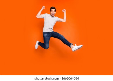 Full length photo of attractive crazy guy jump high supporting favorite football team match game goal wear striped t-shirt jeans shoes isolated bright orange color background - Shutterstock ID 1662064084