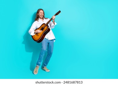 Full length photo of attractive funny guy wear white shirt playing guitar emtpy space isolated blue color background - Powered by Shutterstock