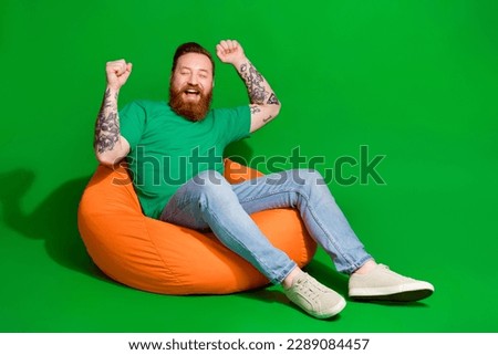Full length photo of attractive lucky man wear t-shirt rising fists shouting empty space isolated green color background