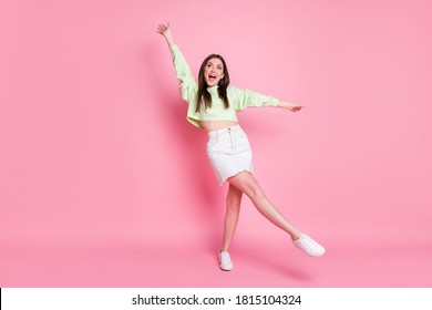 Full length photo of attractive youngster lady raise arms leg high dancing students party good mood wear casual crop pullover naked belly jeans skirt shoes isolated pink color background - Shutterstock ID 1815104324