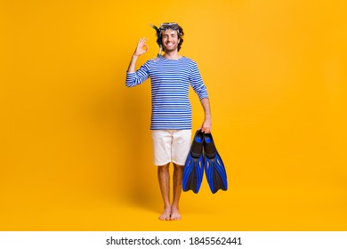 Full Length Photo Of Barefoot Guy Hold Snorkeling Fins Show Okay Sign Wear Mask Goggles Isolated Over Yellow Color Background