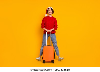 Full Length Photo Of Beautiful Funny Lady Come Winter Holidays Home See Family Hold Rolling Suitcase Airport Wear Santa Cap Red Knitted Sweater Jeans Shoes Isolated Yellow Color Background