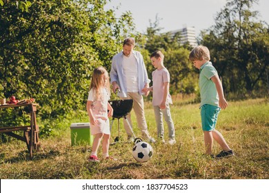 Full Length Photo Of Big Family Four People Two Small Kids Play Football Active Relax Sportive Mood Father Frying Meat Little Brother Help House Green Grass Lawn Garden Trees Backyard Outside