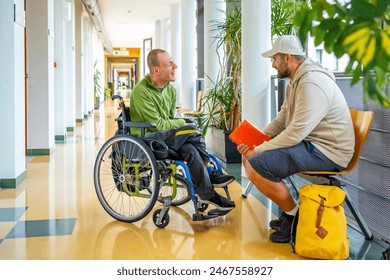 Full length photo of a caucasian adult man with disability talking with a friend sitting in the university