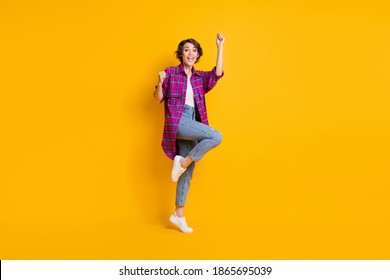 Full length photo charming girl pose win raise fists yes wear jeans plaid shirt isolated on yellow color background - Powered by Shutterstock