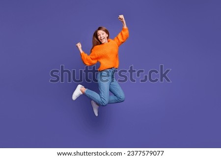 Full length photo of charming young girl jumping after awesome victory in competition raised fists up isolated on purple color background
