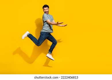 Full length photo of cheerful crazy man hand hold carry empty space dressed stylish clothes isolated on yellow color background
