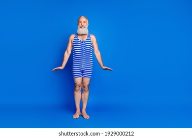 Full length photo of cheerful elderly man wear bathing suit striped copyspace summer swim isolated on blue color background