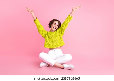 Full length photo of cheerful excited girl dressed neon sweater sitting legs crossed rising hands arms isolated pink color background - Powered by Shutterstock