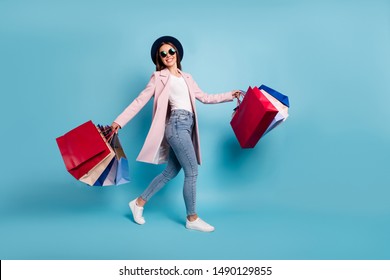 Full Length Photo Of Cheerful Funky Lady Tourist In Eyewear Eyeglasses Go Shopping Buy Sales Discount Wear Pink Retro Vintage Coat Denim Jeans Isolated Over Blue Background