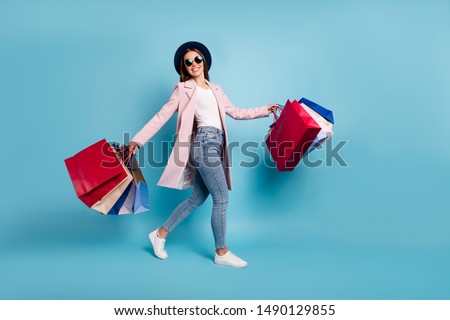 Full length photo of cheerful funky lady tourist in eyewear eyeglasses go shopping buy sales discount wear pink retro vintage coat denim jeans isolated over blue background