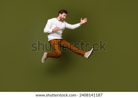 Full length photo of cheerful glad guy wear trendy clothes fly air practicing karate fight empty space isolated on khaki color background
