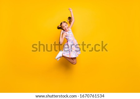 Full length photo of cheerful kid jump enjoy rejoice win lottery sales raise fists scream yeah wear checkered skirt isolated bright shine color background