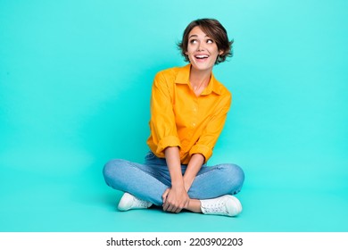 Full length photo of cheerful lady sit floor leg crossed interested look empty space offer promo banner isolated on cyan color background - Shutterstock ID 2203902203
