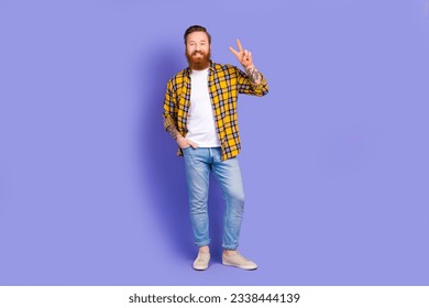Full length photo of cheerful man programmer wear stylish plaid clothes arm demonstrates v-sign isolated on purple color background