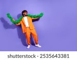 Full length photo of cheerful positive guy dressed orange jacket dancing having fun emtpy space isolated purple color background