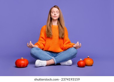 Full length photo of chill young girl closed eyes sitting in lotus position meditation halloween spirit isolated on purple color background