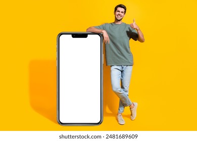 Full length photo of confident cool man dressed khaki t-shirt showing thumb up modern gadget empty space isolated yellow color background - Powered by Shutterstock