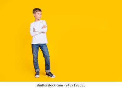 Full length photo of confident thoughtful boy wear white shirt arms crossed looking empty space isolated yellow color background - Powered by Shutterstock