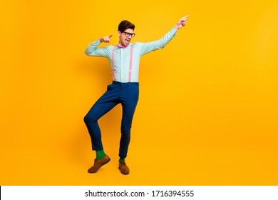 Full Length Photo Of Cool Stylish Guy Boyfriend Dancing Festive Mood Excited Direct Finger Side Wear Specs Shirt Bow Tie Suspenders Trousers Shoes Isolated Vivid Yellow Color Background