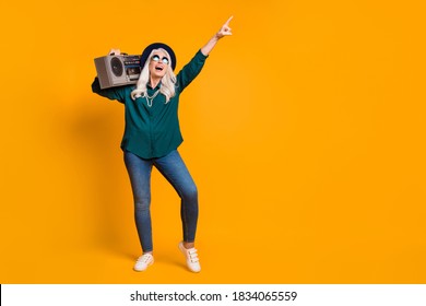 Full Length Photo Of Crazy Granny Lady Senior Party Hold Tape Recorder Shoulder Direct Finger Up Sale Wear Green Shirt Sun Specs Necklace Retro Cap Shoes Isolated Yellow Color Background