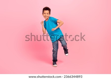 Full length photo of cute carefree small boy wear blue t-shirt dancing having fun isolated pink color background
