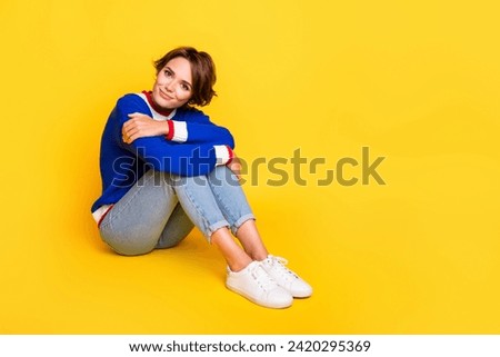 Full length photo of dreamy adorable lady dressed knitted sweater embracing legs empty space isolated yellow color background