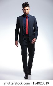 Full Length Photo Of An Elegant Young Fashion Man In Tuxedo Walking Towards The Camera. On Gray Background