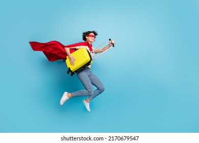 Full Length Photo Of Excited Funky Lady Dressed Red Mantle Jumping Holding Luggage Empty Space Isolated Blue Color Background