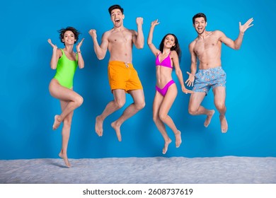 Foto de cuerpo entero de la compañía de los muchachos afortunados emocionados visten los trajes de baño que suben los puños que saltan alto fondo aislado del color azul
