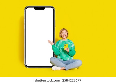 Full length photo of excited positive woman wear green sweatshirt shopping modern device empty space isolated yellow color background