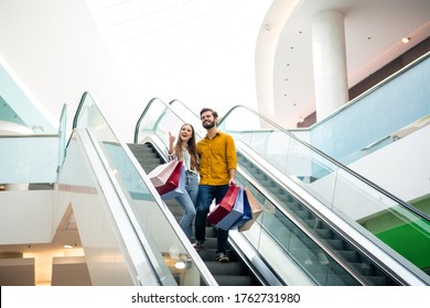 Full Length Photo Of Excited Shocked Two People Couple Move Staircase Look Incredible 50 Sales Girl Point Index Finger Hold Many Packages In Shopping Mall Center