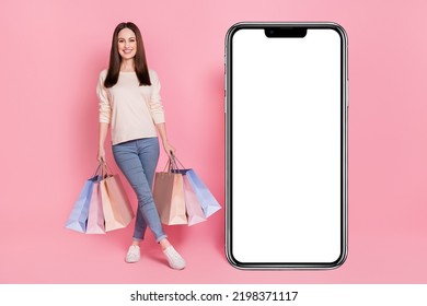 Full Length Photo Of Fashionista Woman With Boutique Packages Presenting Huge Large Phone Touch Screen New Interface Isolated Pink Color Background