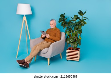 Full length photo of focused man marketing read social media post device sit chair isolated blue color background - Powered by Shutterstock