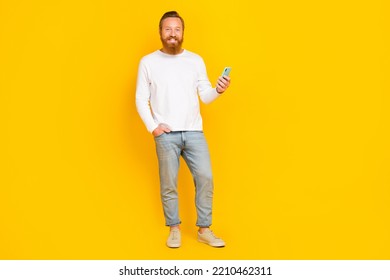 Full length photo of funky beard man hold telephone wear white shirt jeans shoes isolated on yellow color background - Shutterstock ID 2210462311